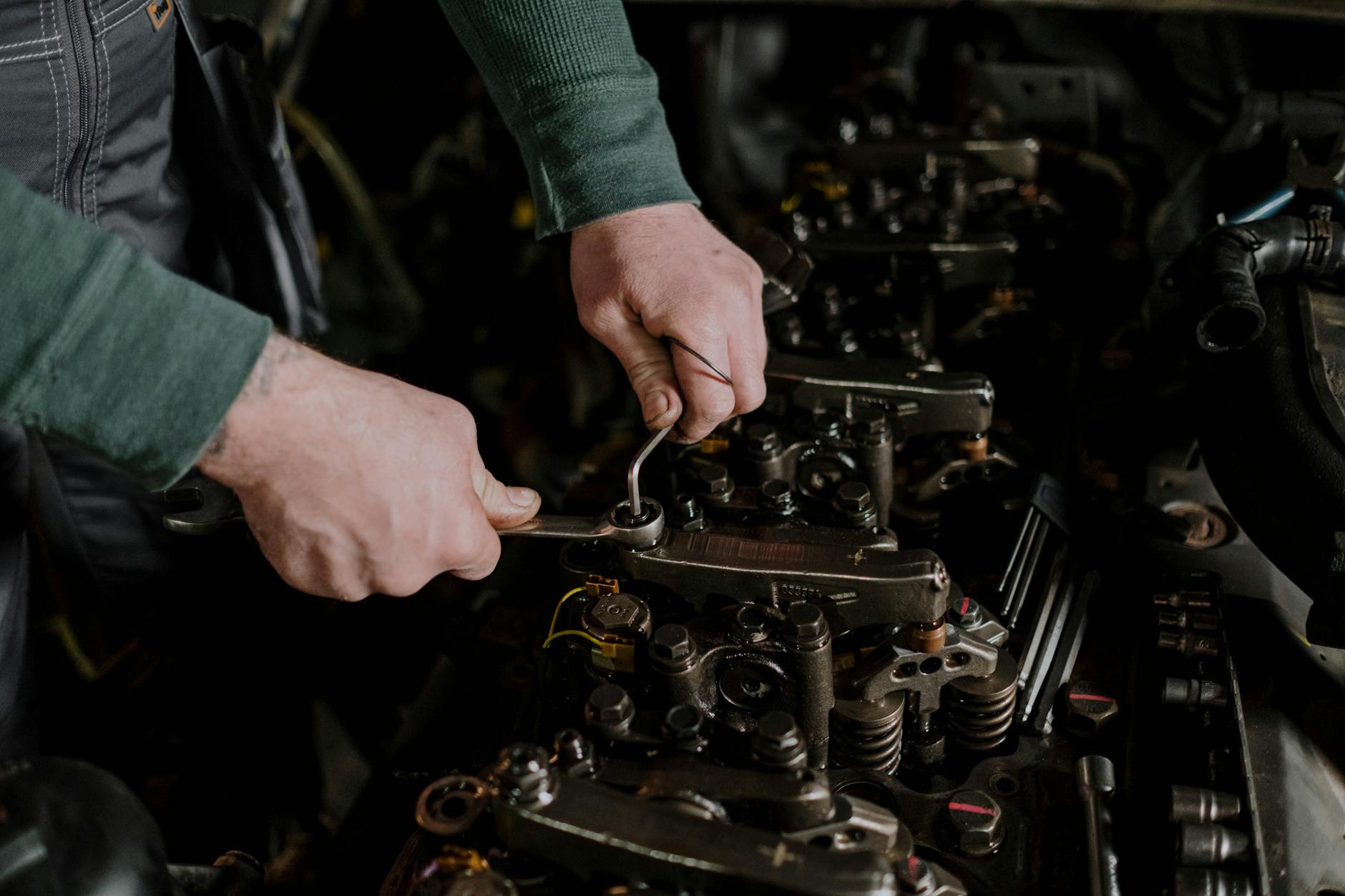 Mechanik naprawiający silnik diesla kluczem w komorze silnika